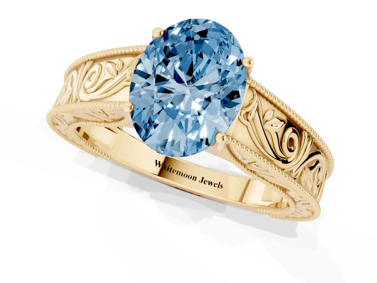 Fancy Blue Oval Cut Diamond Solitaire Ring with Engraved Band and Four-Prong Setting Yellow gold