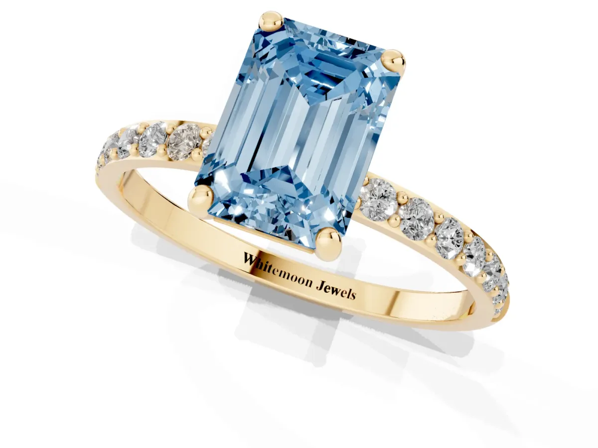 Fancy Blue Emerald Cut Diamond Solitaire Ring with Round Pavé Band and Prong Setting Yellow gold