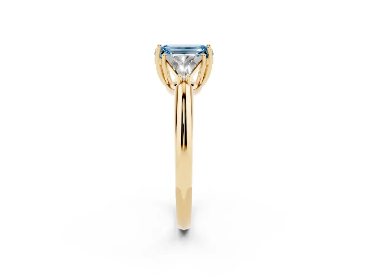 Fancy Blue Three-Stone Emerald Cut Diamond Engagement Ring with Trillion Side Stones and Prong Setting Yellow gold