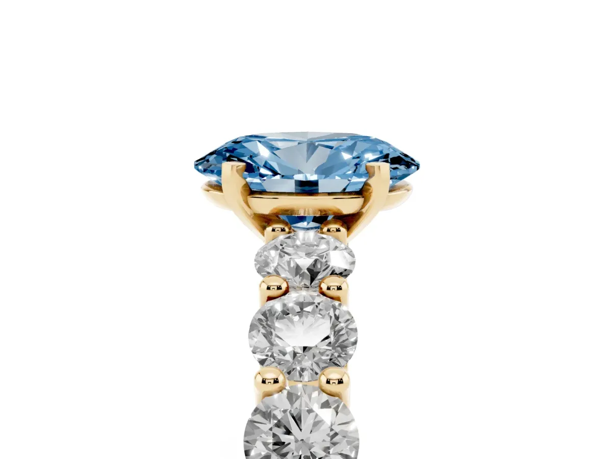 Fancy Blue Oval Cut Diamond Prong Setting with Side Stones on a Pave Band Yellow gold