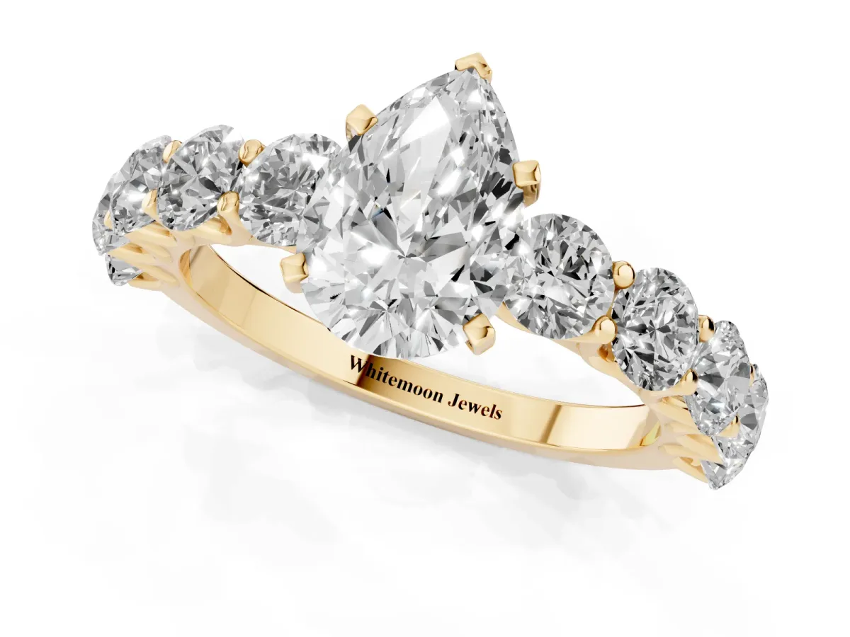 Pear Cut Diamond Prong Setting with Side Stones on a Pave Band Yellow gold
