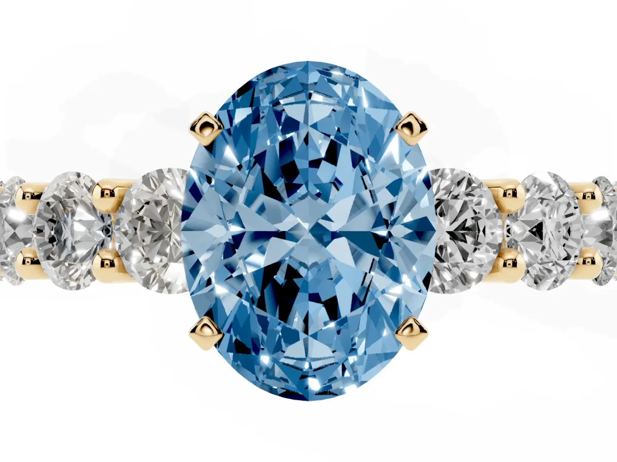 Fancy Blue Oval Cut Diamond Prong Setting with Side Stones on a Pave Band Yellow gold