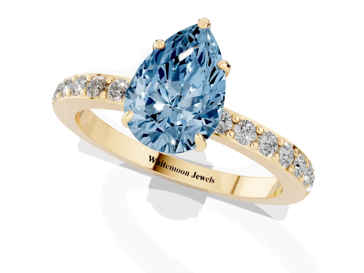 Fancy Blue Pear Cut Diamond Pavé Engagement Ring with Round Accents and Prong Setting Yellow gold