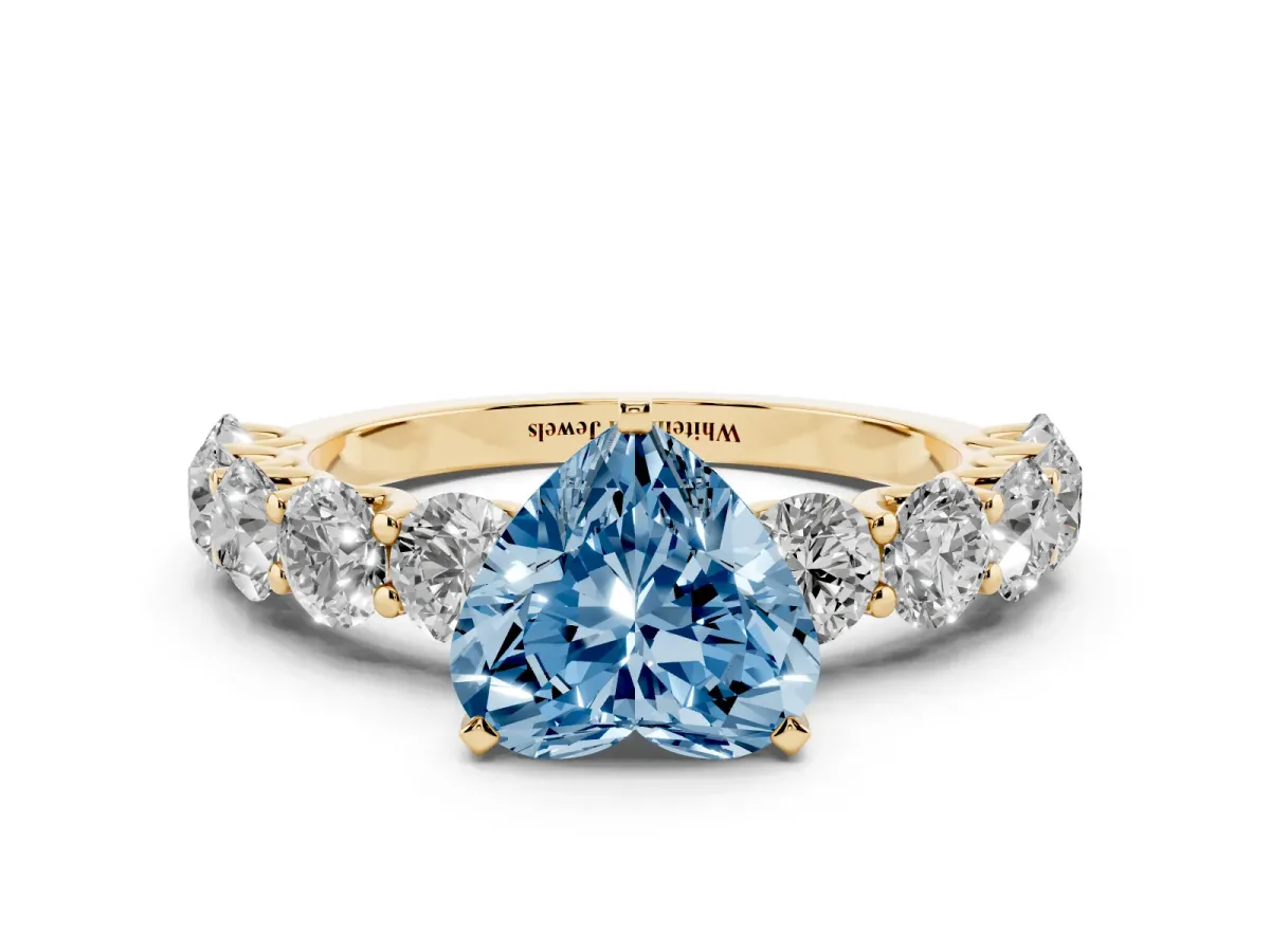 Fancy Blue Heart Cut Diamond Prong Setting with Side Stones on a Pave Band Yellow gold