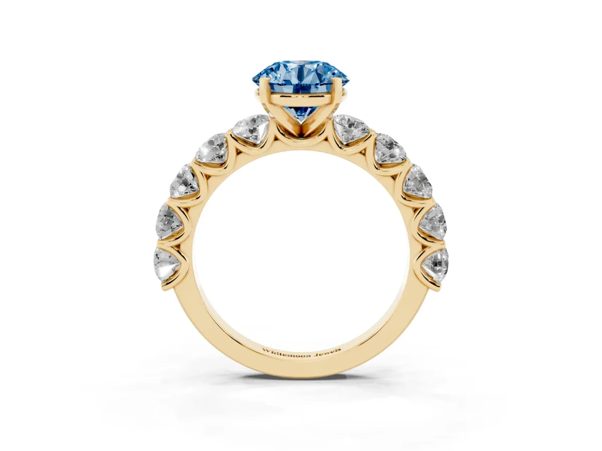 Fancy Blue Round Cut Diamond Prong Setting with Side Stones on a Pave Band Yellow gold