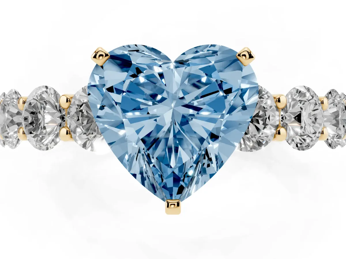 Fancy Blue Heart Cut Diamond Prong Setting with Side Stones on a Pave Band Yellow gold