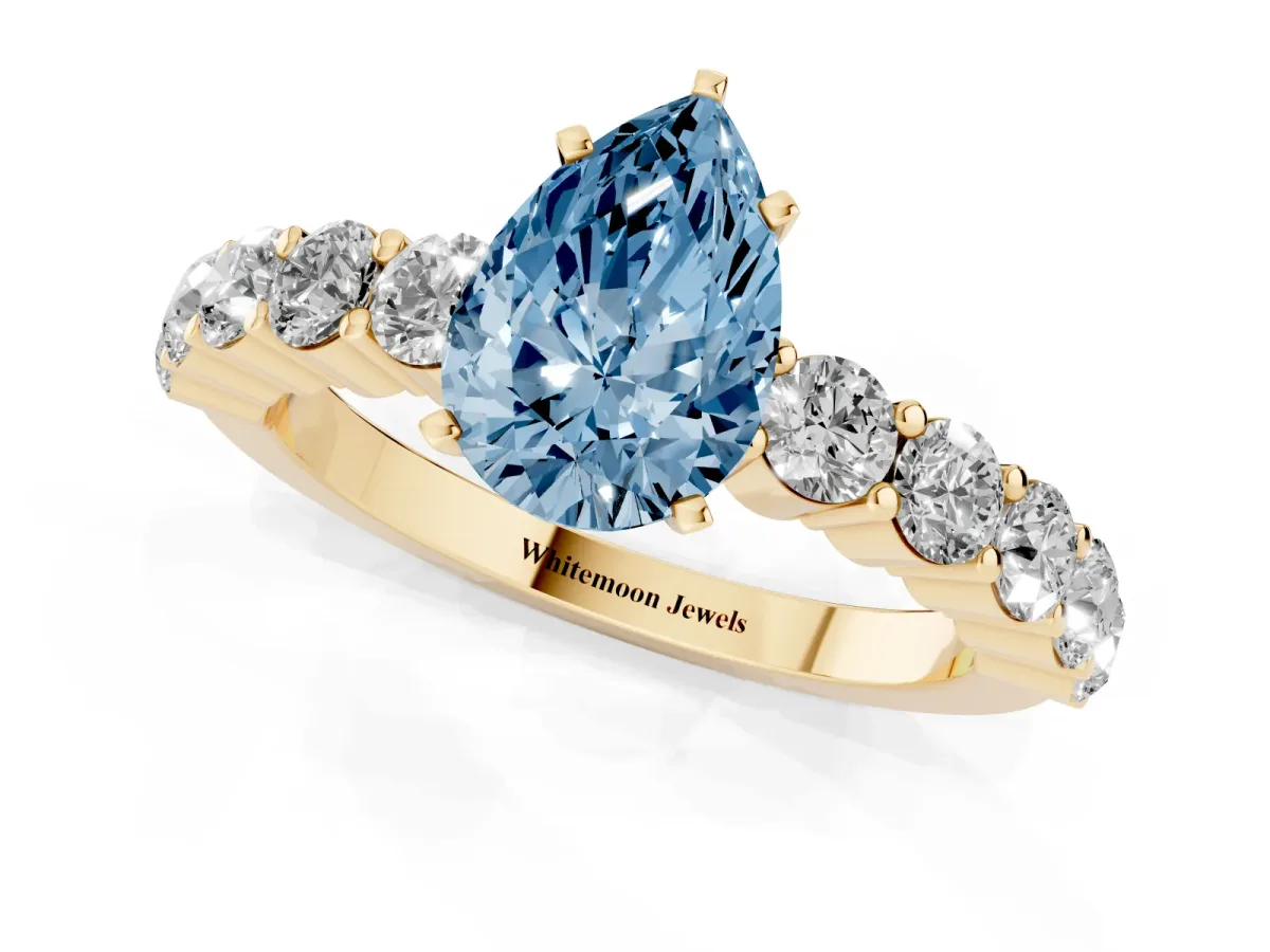 Fancy Blue Pear Cut Diamond Solitaire Ring with Shared Prong Round Side Stones Yellow gold