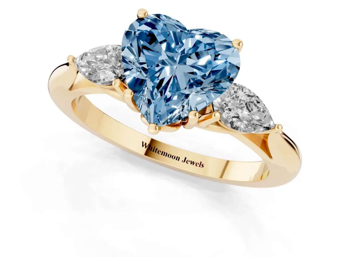 Fancy Blue Three-Stone Heart Cut Brilliant Diamond Solitaire Ring with Tapered Band and Four-Prong Setting Yellow gold