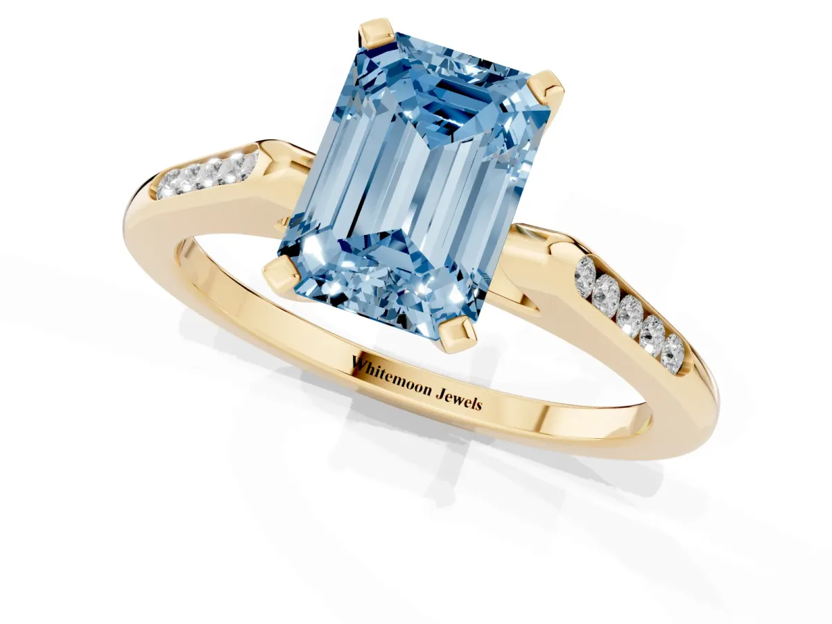 Fancy Blue Emerald Cut Diamond Solitaire Ring with Channel Set Round Band and Prong Setting Yellow gold