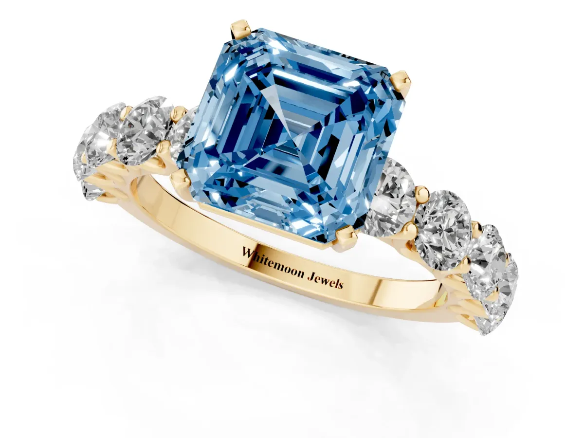 Fancy Blue Asscher Cut Diamond Prong Setting with Side Stones on a Pave Band Yellow gold