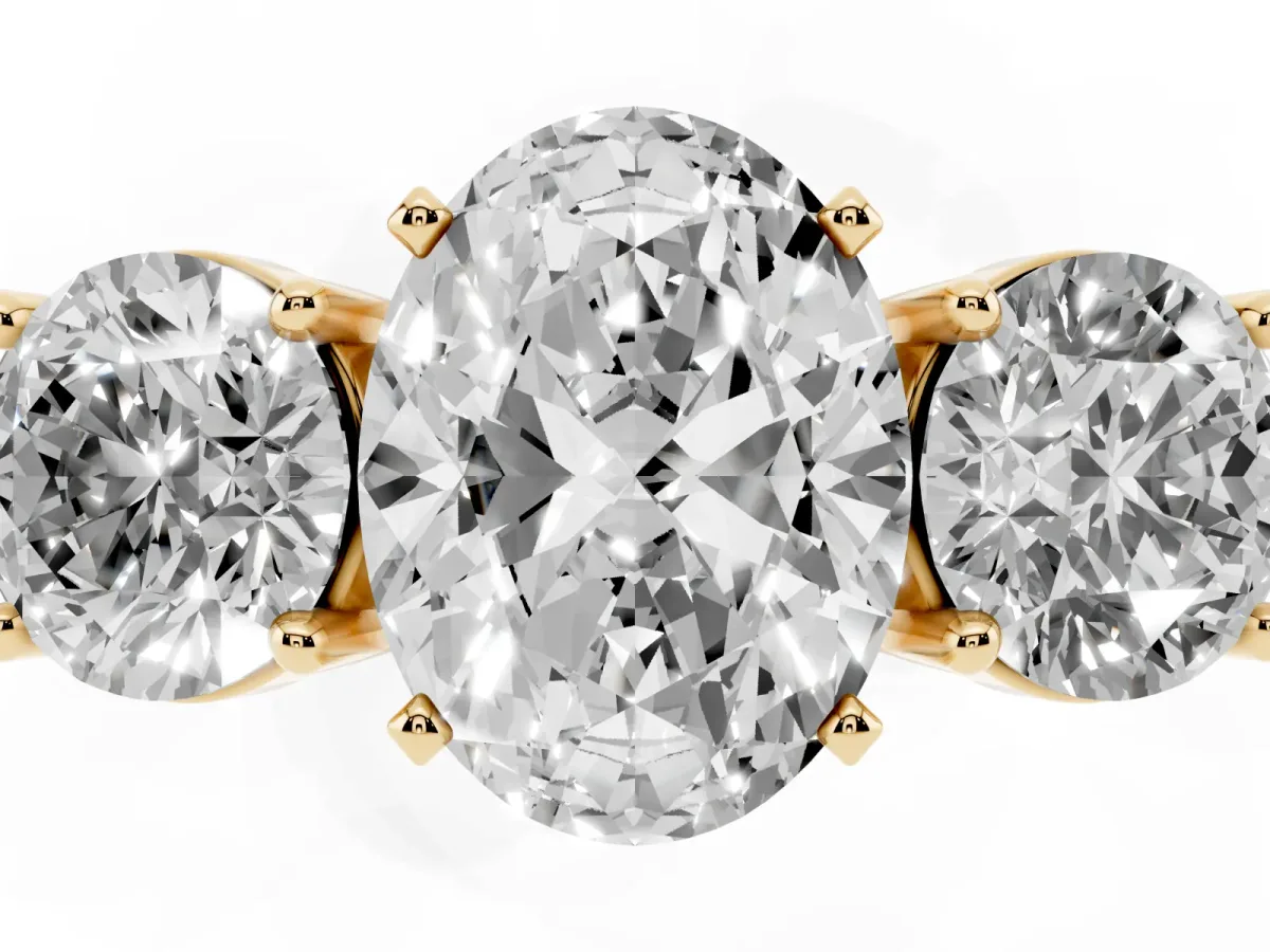 Three-Stone Oval Cut Diamond Ring with Round Side Stones, Classic Band, and Four-Prong Setting Yellow gold