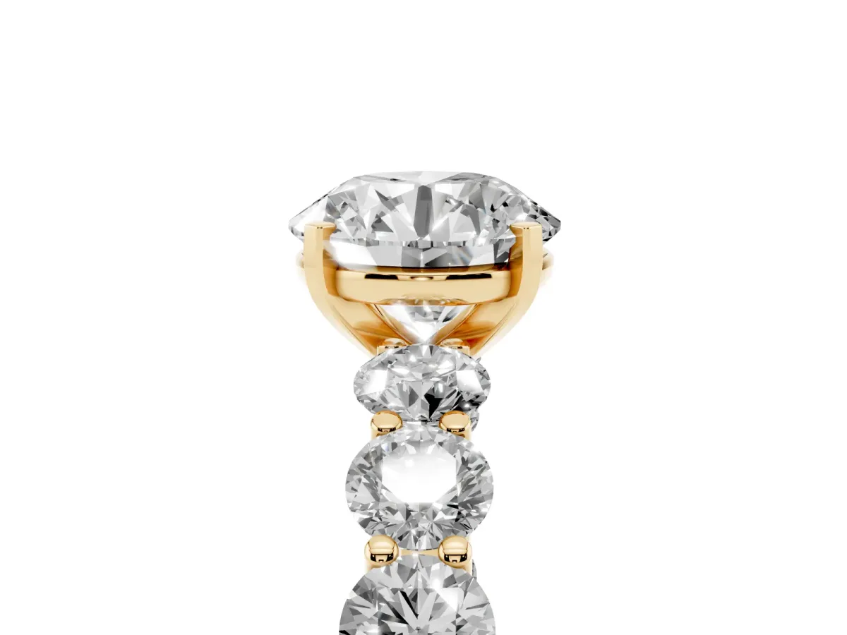 Round Cut Diamond Prong Setting with Side Stones on a Pave Band Yellow gold