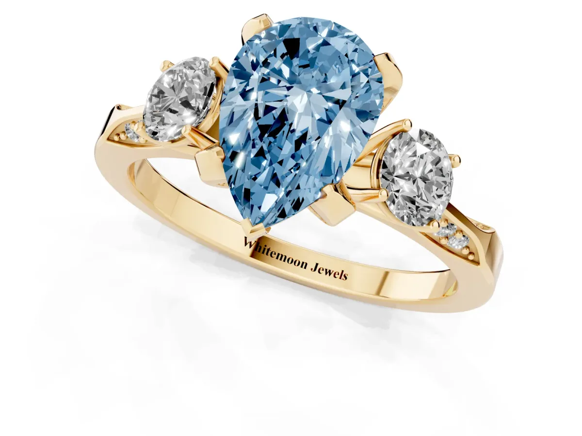 Fancy Blue Pear Cut Brilliant Three-Stone Diamond Ring with Pavé Band and Four-Prong Setting Yellow gold