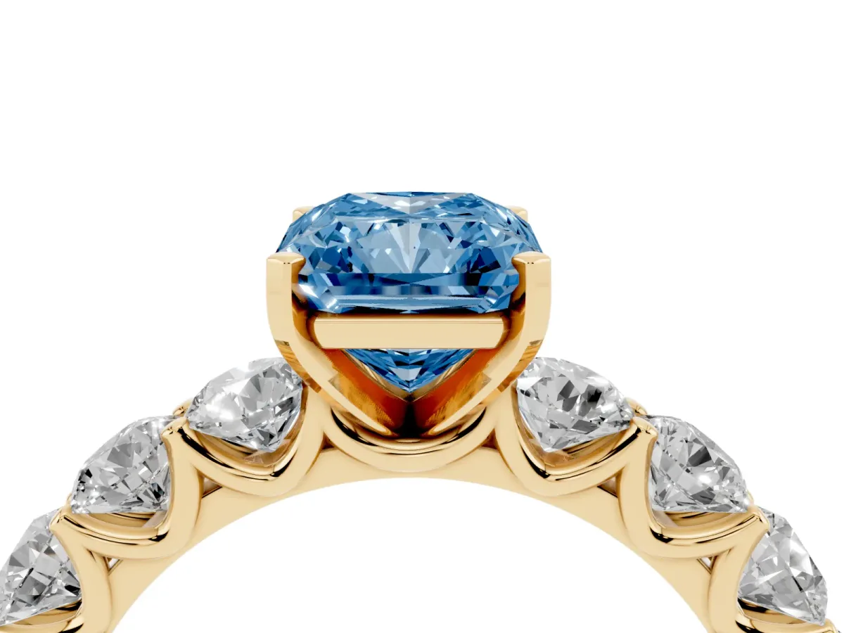 Fancy Blue Radiant Cut Diamond Prong Setting with Side Stones on a Pave Band Yellow gold