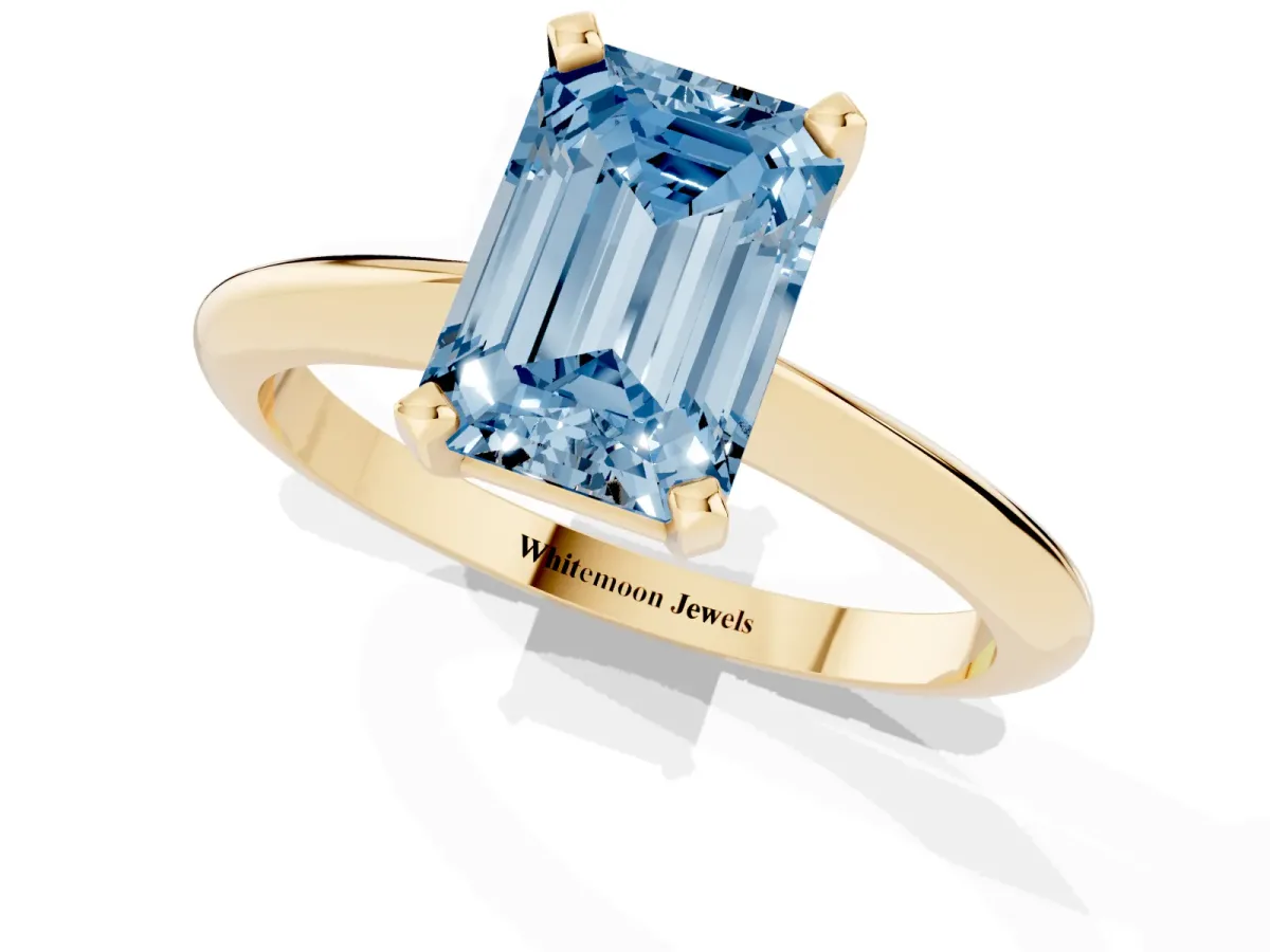 Fancy Blue Emerald Cut Cut Solitaire Ring with Four-Prong Setting on a Classic Band Yellow gold