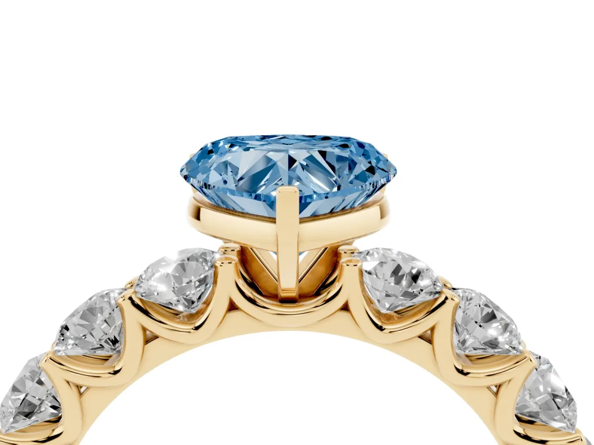 Fancy Blue Heart Cut Diamond Prong Setting with Side Stones on a Pave Band Yellow gold