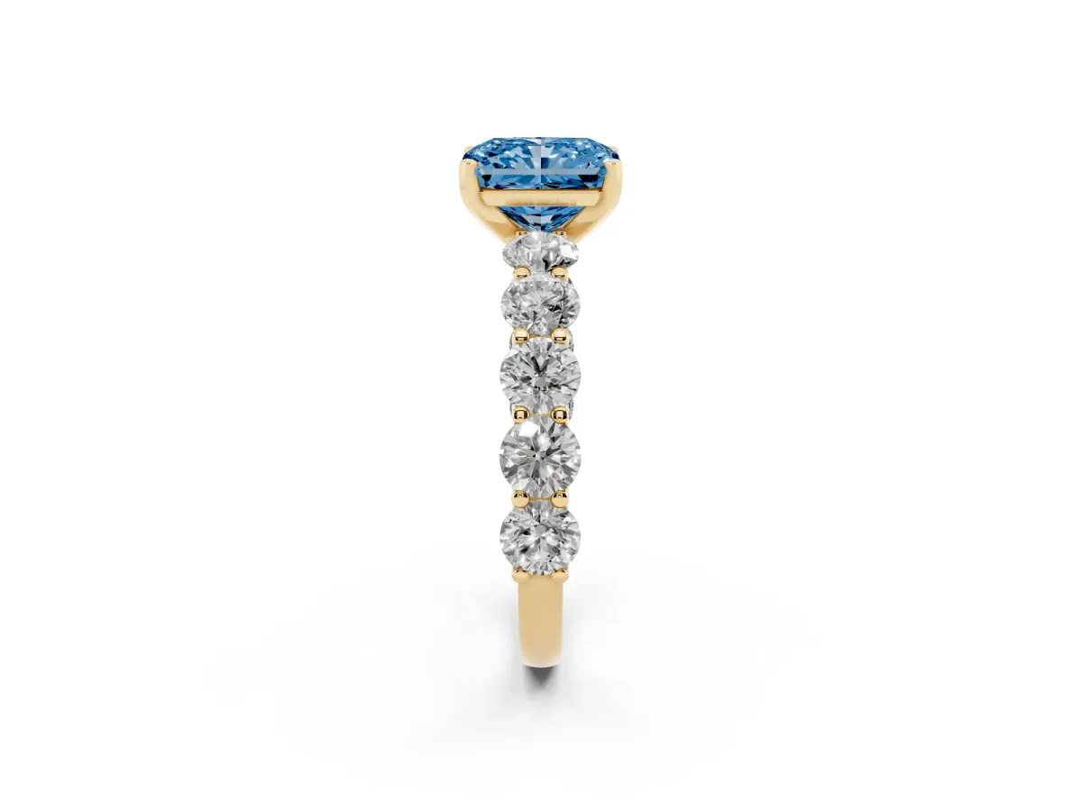 Fancy Blue Radiant Cut Diamond Prong Setting with Side Stones on a Pave Band Yellow gold
