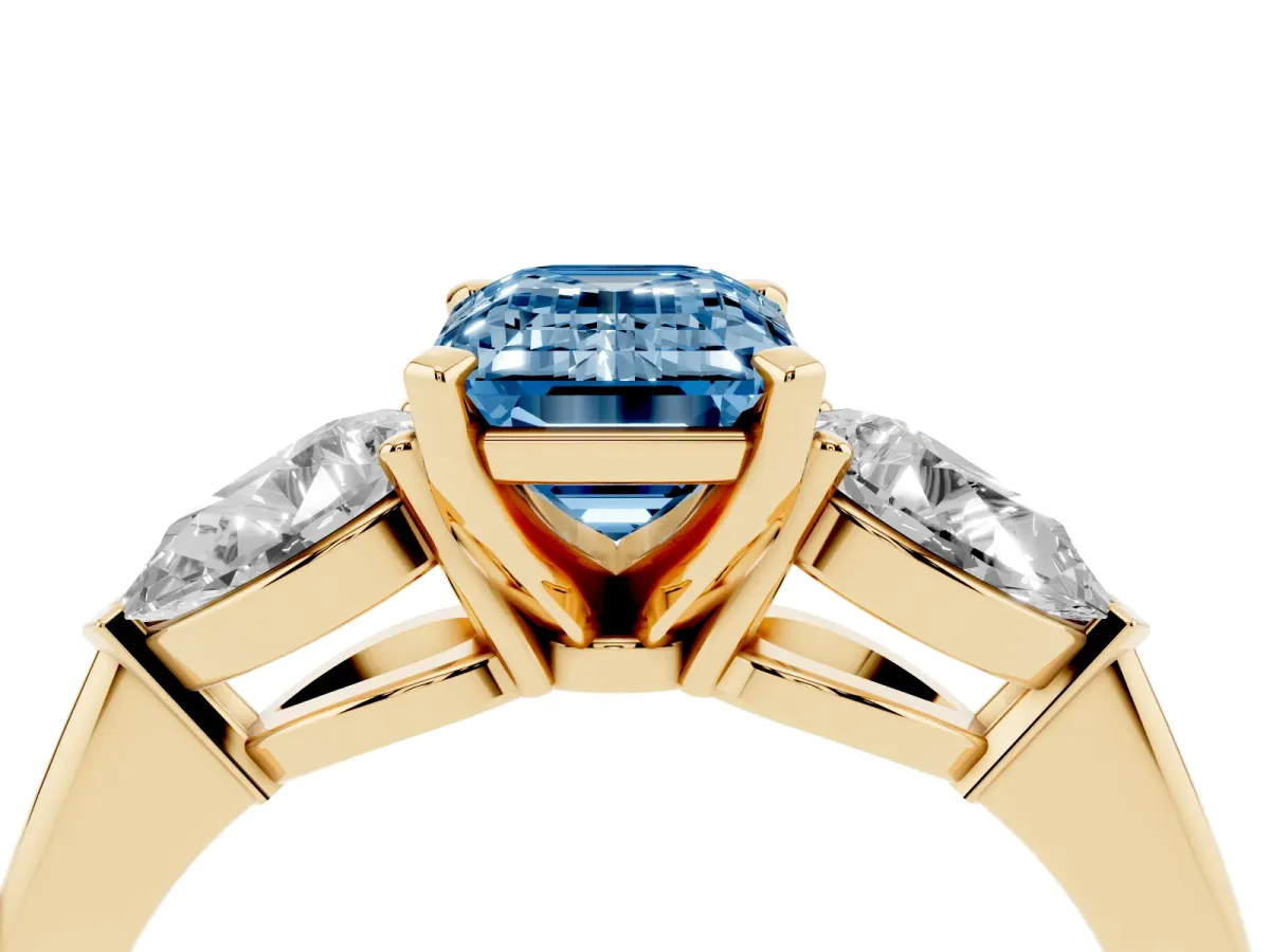 Fancy Blue Three-Stone Emerald Cut Diamond Ring with Pear Side Stones and Four-Prong Setting Yellow gold