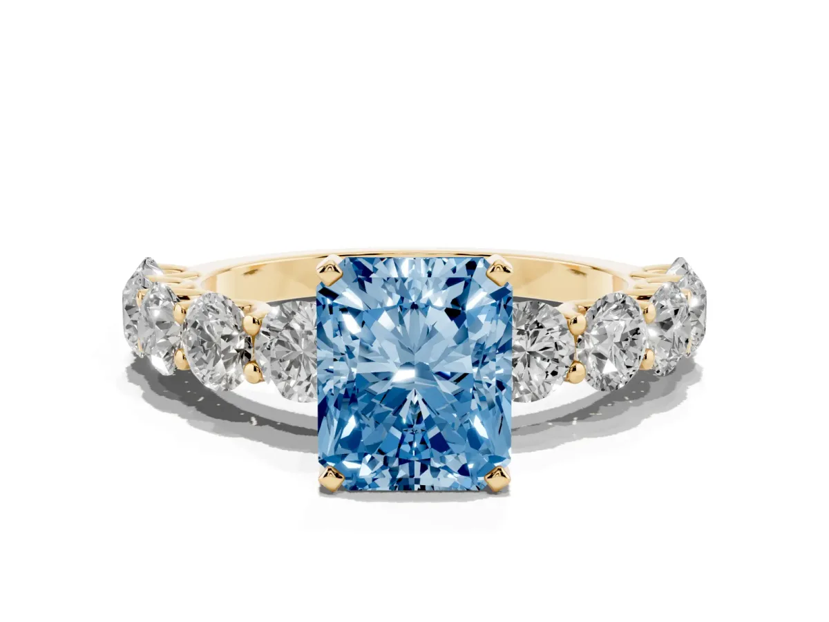 Fancy Blue Radiant Cut Diamond Prong Setting with Side Stones on a Pave Band Yellow gold