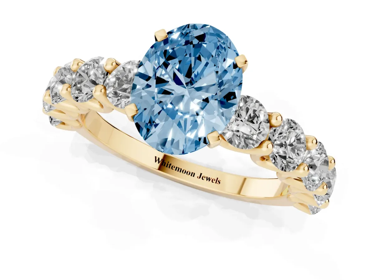 Fancy Blue Oval Cut Diamond Prong Setting with Side Stones on a Pave Band Yellow gold