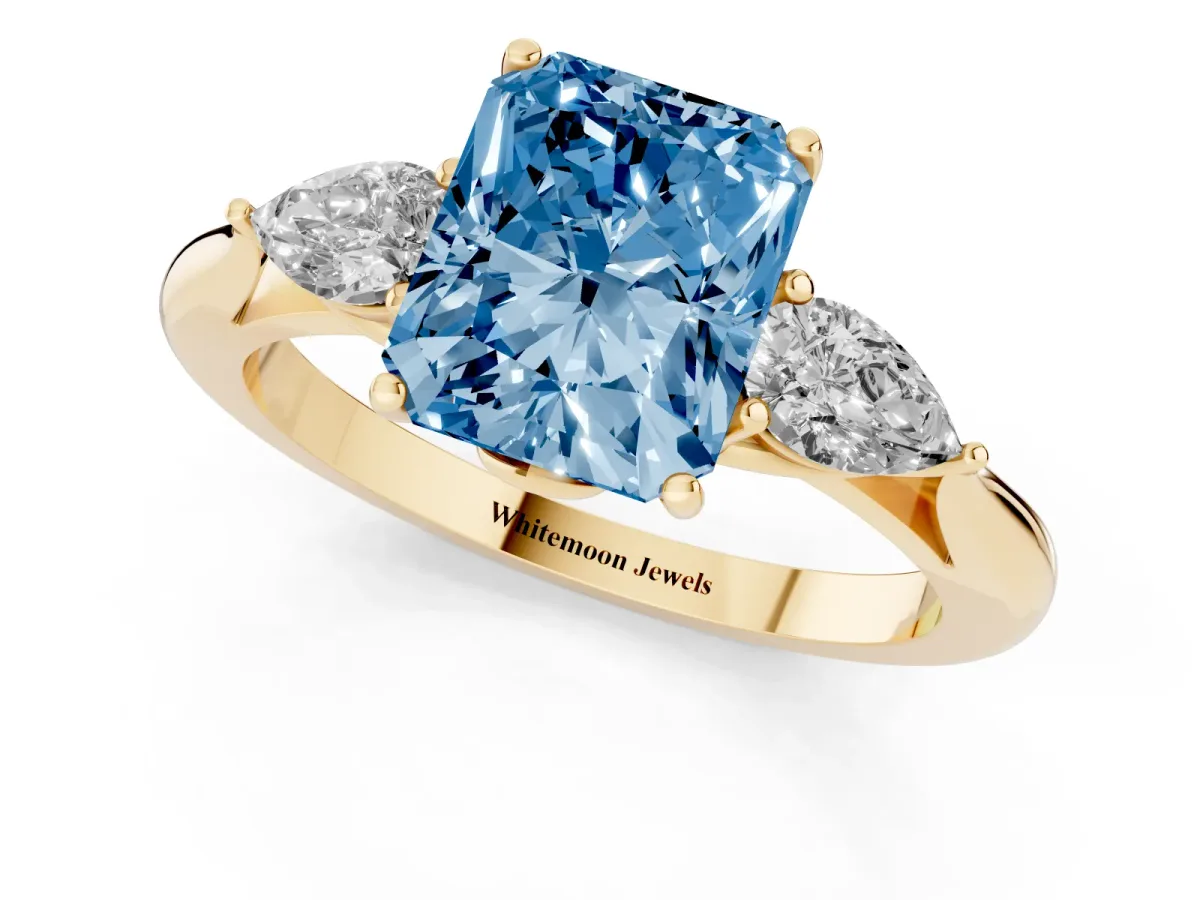 Fancy Blue Three-Stone Radiant Cut Diamond Ring with Pear Side Stones in Four-Prong Setting Yellow gold