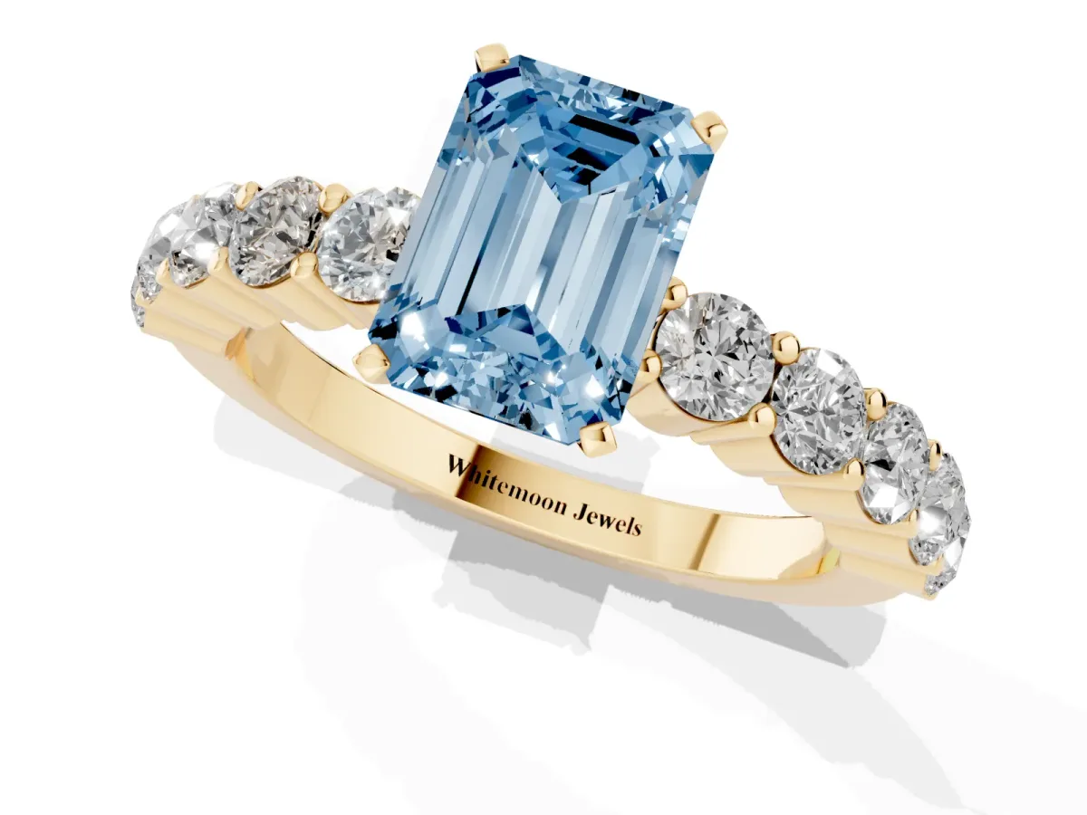 Fancy Blue Emerald Cut Diamond Solitaire Ring with Shared Prong Round Side Stones Yellow gold