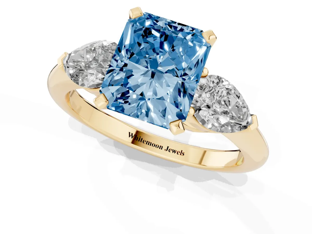 Fancy Blue Three-Stone Radiant Cut Diamond Ring with Pear Side Stones and Four-Prong Setting Yellow gold
