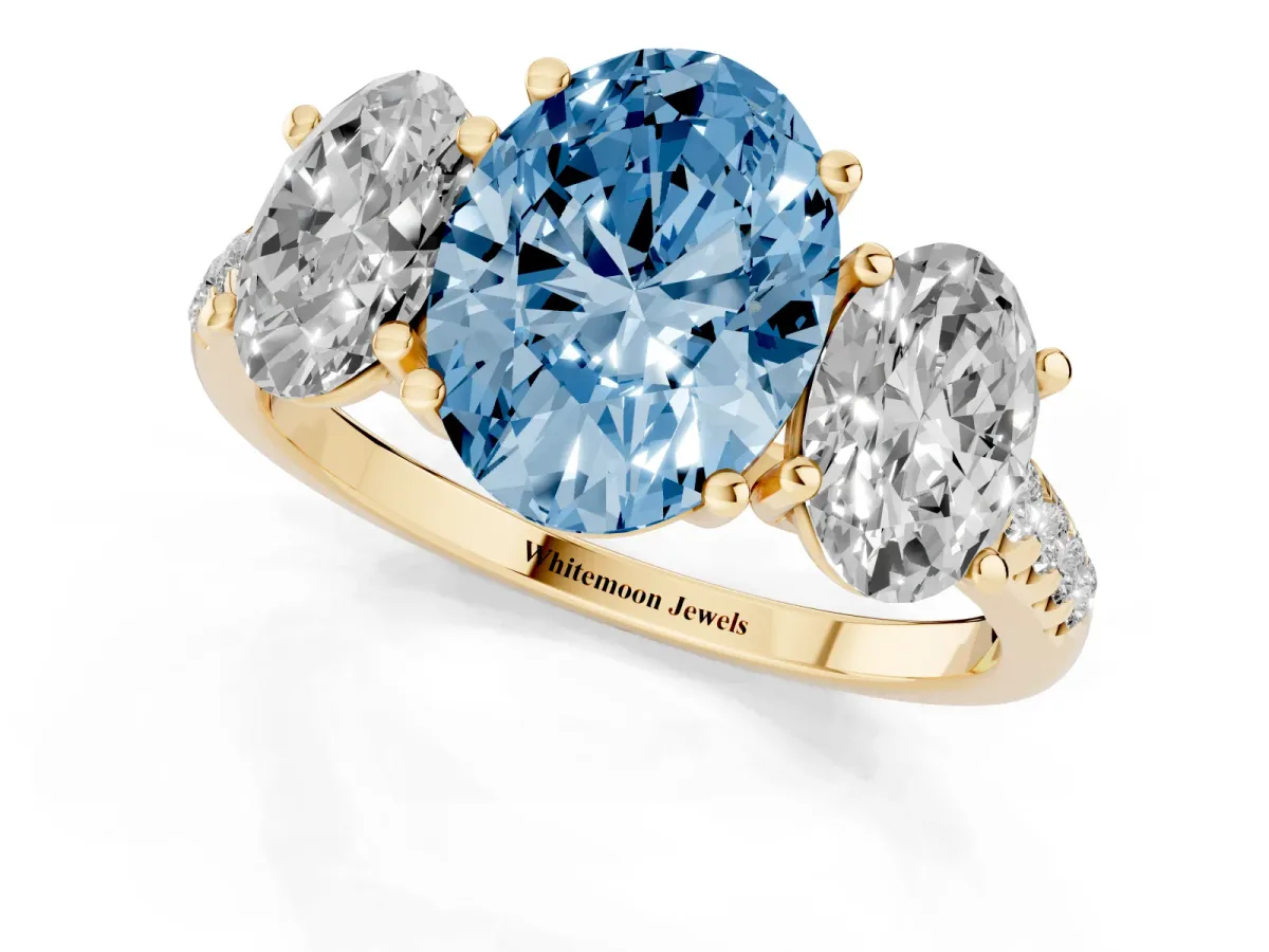 Fancy Blue Three-Stone Oval Cut Diamond Ring with Round Pavé Band and Prong Setting Yellow gold