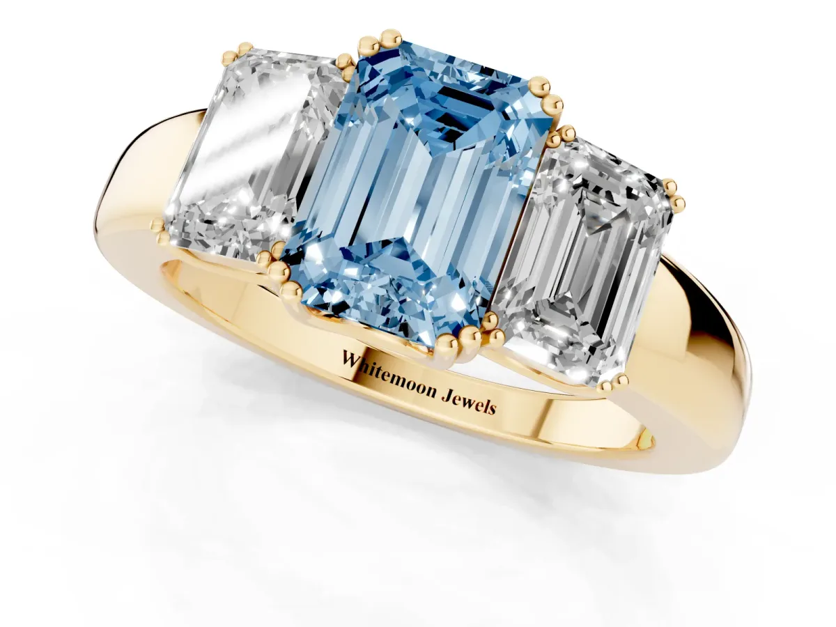 Fancy Blue Three-Stone Emerald Cut Cut Diamond Ring with Channel Set Band and Four-Prong Setting Yellow gold