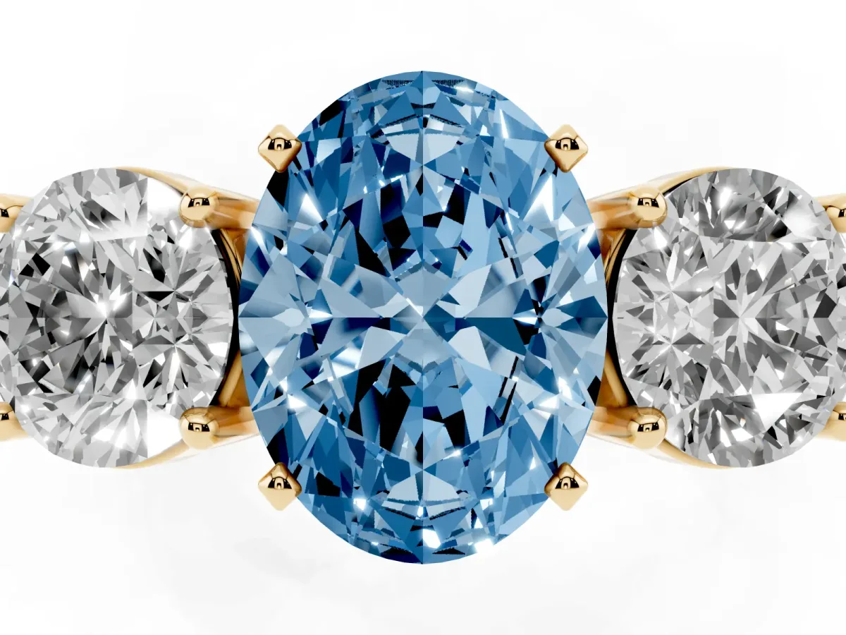 Fancy Blue Three-Stone Oval Cut Diamond Ring with Round Side Stones, Classic Band, and Four-Prong Setting Yellow gold