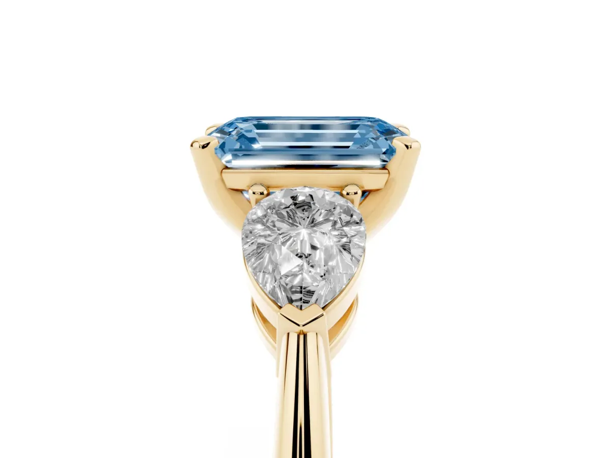 Fancy Blue Three-Stone Emerald Cut Diamond Ring with Pear Side Stones and Four-Prong Setting Yellow gold
