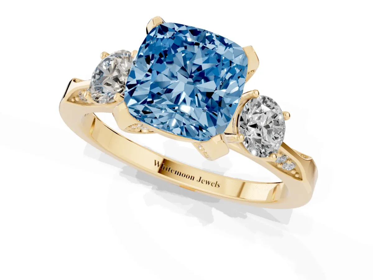 Fancy Blue Cushion Cut Brilliant Three-Stone Diamond Ring with Pavé Band and Four-Prong Setting Yellow gold