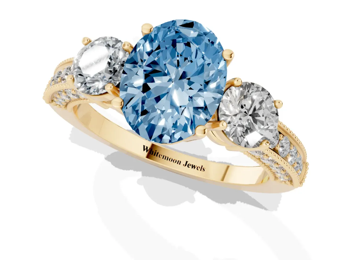Fancy Blue Oval Cut Three-Stone Diamond Ring with Pavé Band and Four-Prong Setting Yellow gold