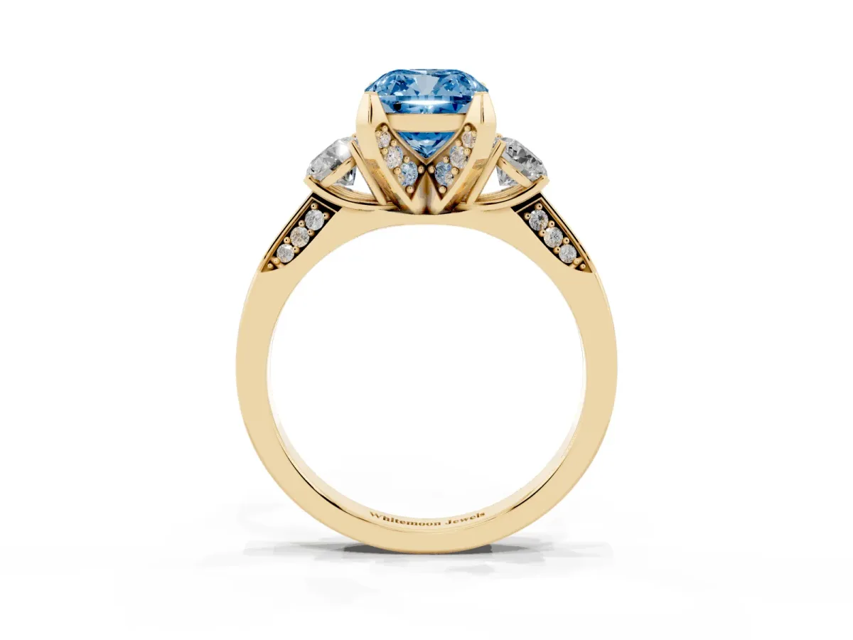 Fancy Blue Cushion Cut Brilliant Three-Stone Diamond Ring with Pavé Band and Four-Prong Setting Yellow gold