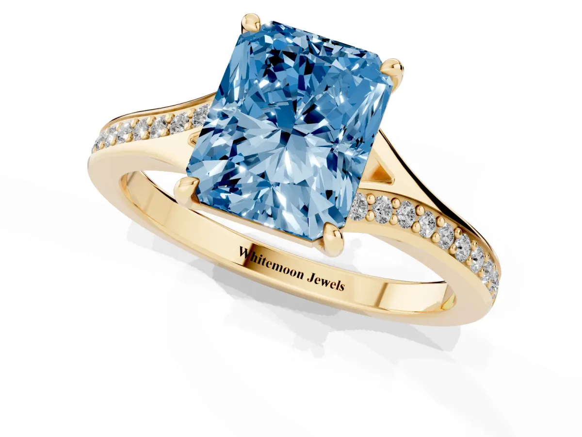 Fancy Blue Radiant Cut Diamond Solitaire Ring with Pavé Band and Prong Setting Yellow gold
