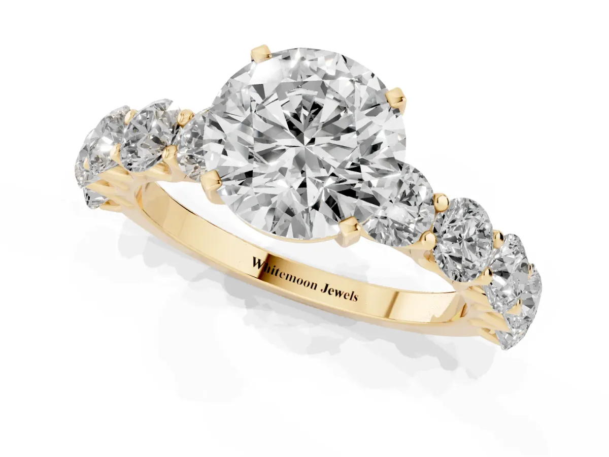 Round Cut Diamond Prong Setting with Side Stones on a Pave Band Yellow gold
