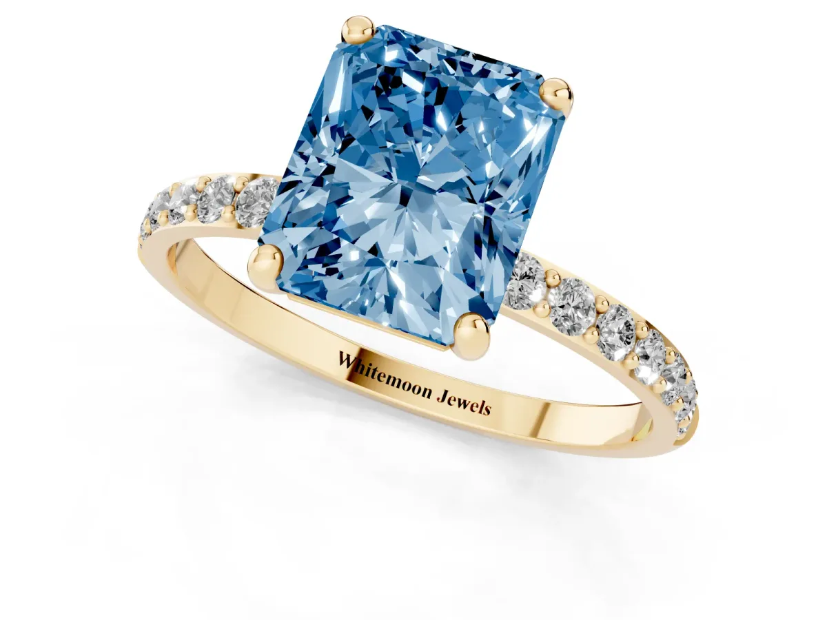 Fancy Blue Radiant Cut Diamond Solitaire Ring with Round Pavé Band and Prong Setting Yellow gold