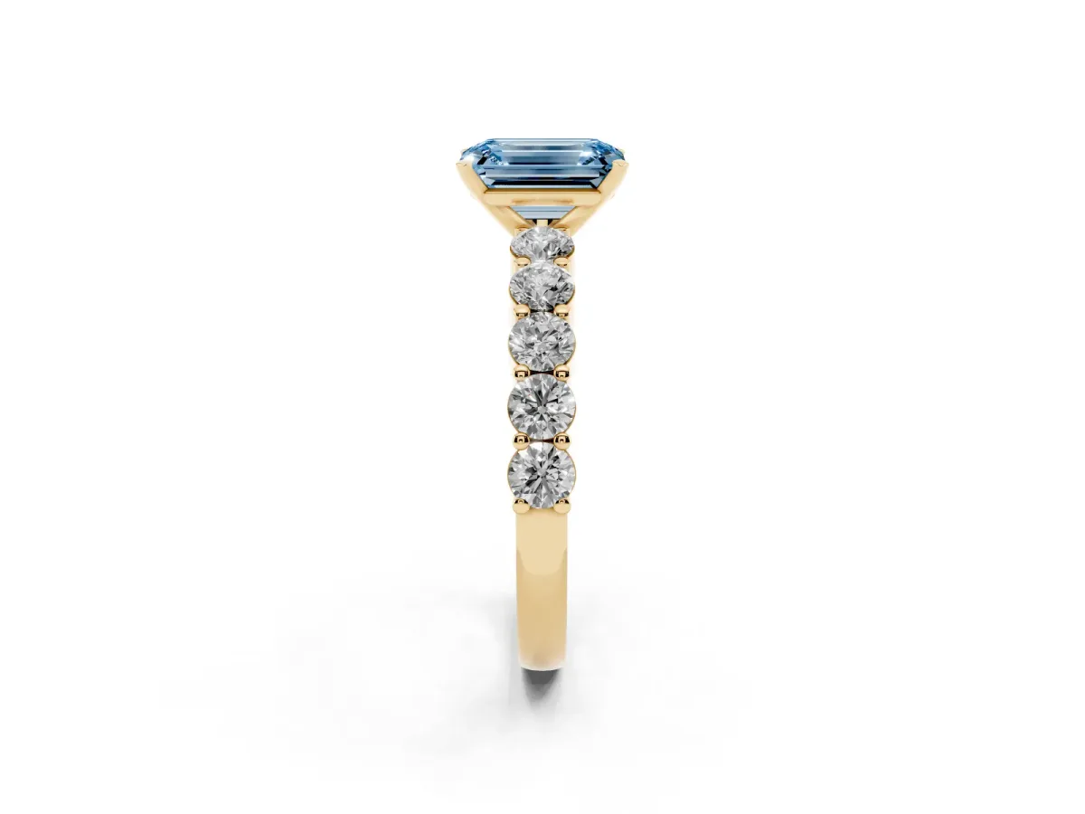 Fancy Blue Emerald Cut Diamond Solitaire Ring with Shared Prong Round Side Stones Yellow gold
