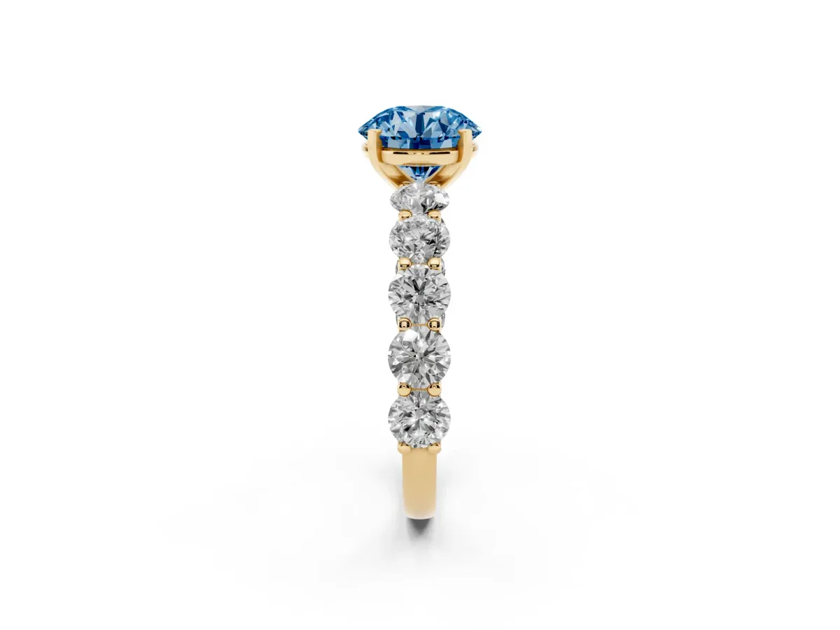 Fancy Blue Round Cut Diamond Prong Setting with Side Stones on a Pave Band Yellow gold