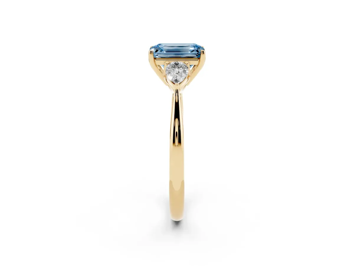 Fancy Blue Three-Stone Emerald Cut Diamond Ring with Pear Side Stones in Four-Prong Setting Yellow gold