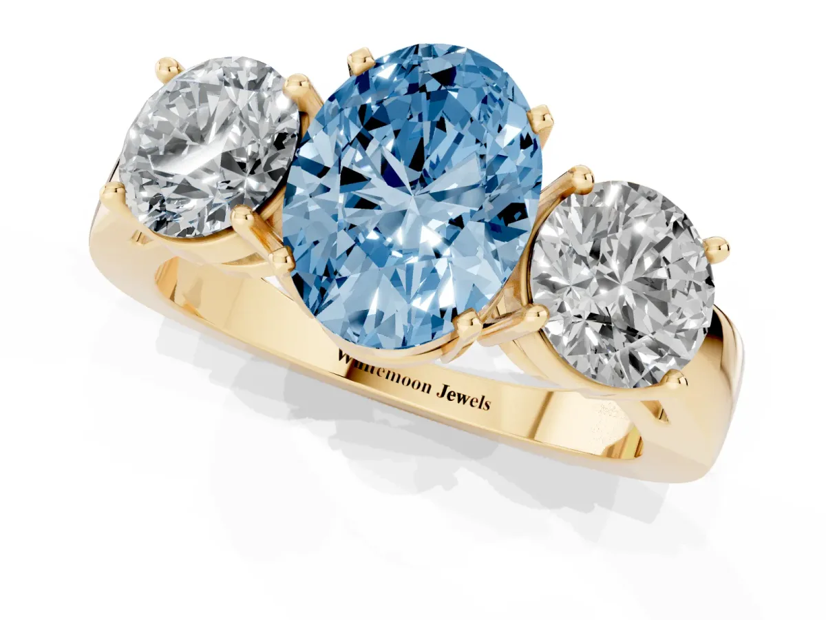 Fancy Blue Three-Stone Oval Cut Diamond Ring with Round Side Stones, Classic Band, and Four-Prong Setting Yellow gold