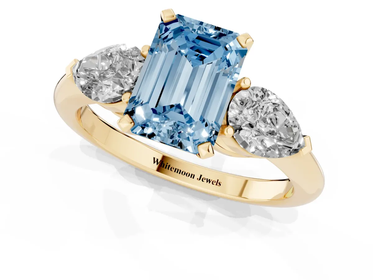 Fancy Blue Three-Stone Emerald Cut Diamond Ring with Pear Side Stones and Four-Prong Setting Yellow gold