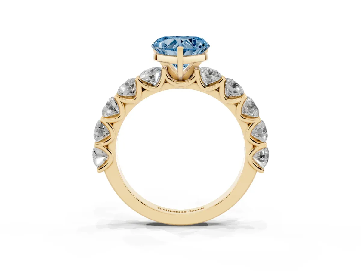 Fancy Blue Heart Cut Diamond Prong Setting with Side Stones on a Pave Band Yellow gold
