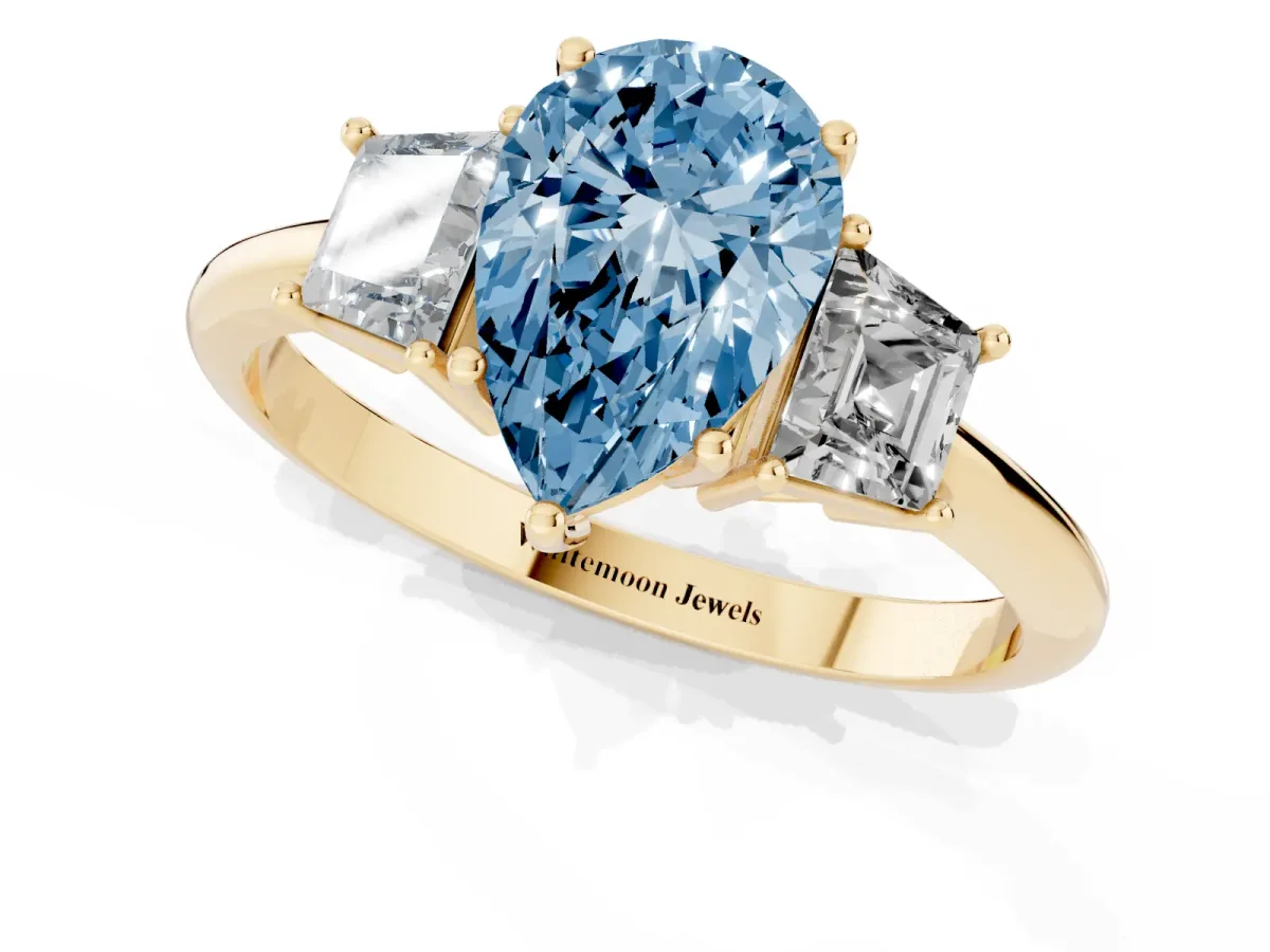 Fancy Blue Pear Cut Diamond Three-Stone Ring with Trapezoid Side Stones and Prong Setting Yellow gold