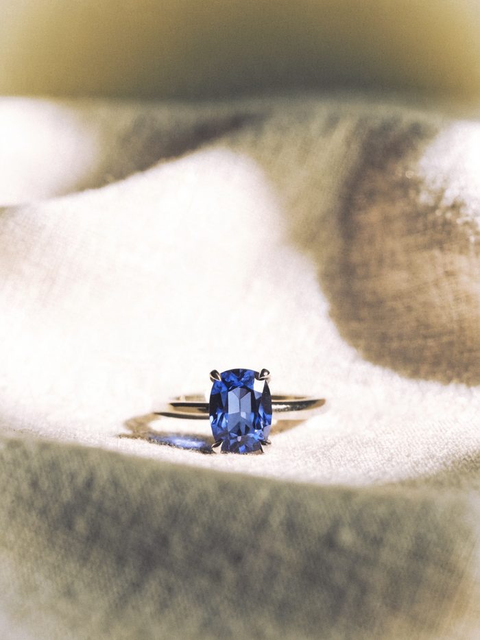 A cushion-cut blue sapphire solitaire ring on linen